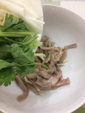 拿个大碗将切好的猪耳放入，在把香菜放入
