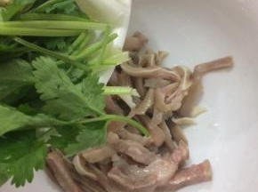 拿个大碗将切好的猪耳放入，在把香菜放入

