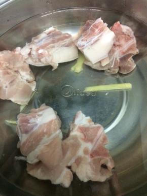 汤锅里加入适量的水，把生姜和适量的料酒放入锅中，再把大骨放入锅中，焯水去除血水