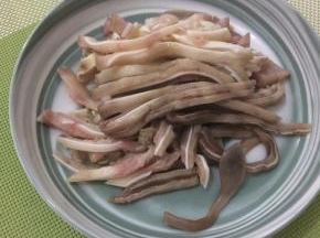煮熟的猪耳放入冰水中冰一下，使猪耳更加的脆，然后捞出沥干水分，用刀一切两半，厚的地方用刀片一下，最后切成粗条备用
