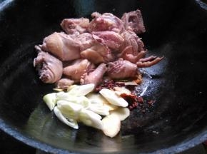 煸炒出水汽,鸡块变白,推至锅边,下葱姜片、干调料煸香。