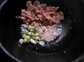 肉片推至锅边，放入葱花、一半蒜末，煸出香味。