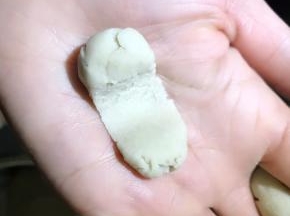 5.取一小点面放于手掌，用右手拇指中间推压一下