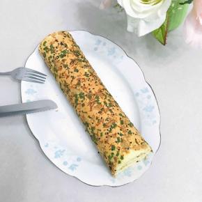 出炉后震二下，拿起油布拖出烤盘移至烤网上稍凉后翻面，撕开油布，表面再盖上油布或者油纸防干，微微手温靠自己的一边钭切一刀，连同油布慢慢卷起，放入冰箱冷藏半小时