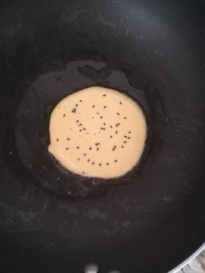 撒上一点熟黑芝麻。等到底面凝固后。翻面。
