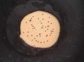 撒上一点熟黑芝麻。等到底面凝固后。翻面。