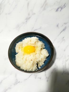 在热腾腾的米饭上打一个鸡蛋，鸡蛋的蛋黄像太阳一样装饰着米饭
