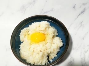 在热腾腾的米饭上打一个鸡蛋，鸡蛋的蛋黄像太阳一样装饰着米饭
