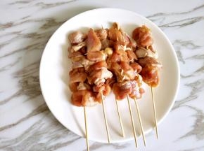 用竹签把腌制好的鸡腿串成串
