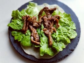 再一张薄饼上铺一片洗干净并淋干水份的生菜叶，再铺上适量的牛肉条。