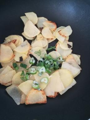 土豆片焦黄之后，加入剩余的葱圈翻炒。