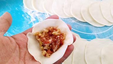 取一个饺子皮，中间放馅。