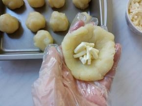 把球按扁，包入马苏里拉奶酪，收口包紧，再搓成圆球。