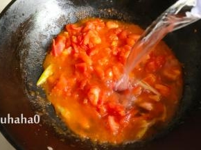 西红柿炒制变软起沙后加入少许的白糖，炒匀后加入清水