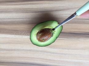 用勺子挖去果核，然后用刀在果肉上划十字
