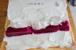 蛋糕卷下面垫保鲜膜，蛋糕卷两边切斜刀涂抹在已脱模的蛋糕卷上，两头奶油略薄一些， 中间放上火龙果在上面盖上奶油