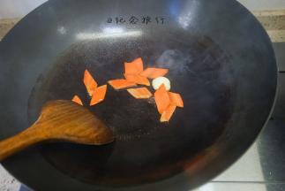 热锅冷油加入拍扁的大蒜还有胡萝卜翻炒