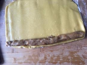 将馅料装入袋子搓成长条状，与面团一样的长度， 然后将其摆放到面擀好的面片边缘处。