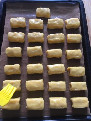 将切好的小面坯摆放入铺有油纸的烤盘中，在表面刷一层蛋黄液，并撒上适量白芝麻。