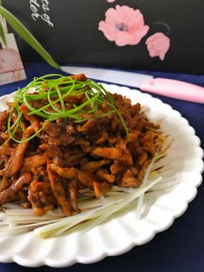 把切成细丝的葱白铺在盘子底部，放上炒好的肉丝，再把葱绿丝撒在肉丝上。