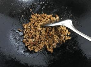 等到炒至酱汁变得浓稠时，放入肉丝，不停地翻炒，使甜面酱均匀地沾在肉丝上。