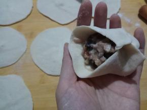 将面剂按扁，擀成圆皮，包入馅料，收口。