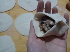 将面剂按扁，擀成圆皮，包入馅料，收口。