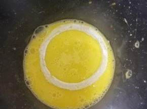 粘好裹粉的洋葱圈，放入鸡蛋液中，溜一圈。