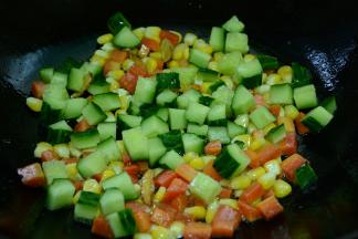 接着再加入玉米粒和黄瓜翻炒出香味。