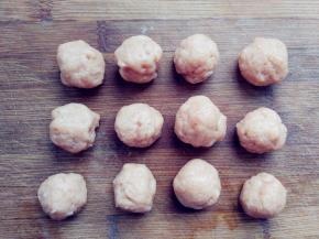 蒸发糕的同时，将搅好的肉馅用勺子舀在手心里，手掌半握，将肉馅从虎口中挤出，形成大小适中的丸子