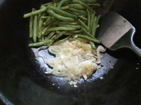 豆角很嫩，不用太长时间，就已经八成熟了。将豆角用锅铲推至锅边，加葱、姜、蒜末（用一半）爆香。