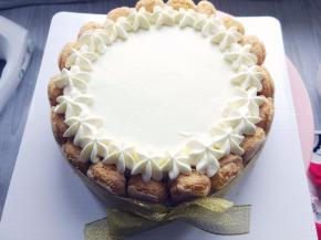 将手指饼干对半切成适当长短，围在蛋糕四周，用丝带在外圈扎好蝴蝶结