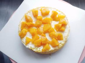 在分片的蛋糕胚上涂少许淡奶油，将沥净糖水并切块的黄桃罐头撒在上面