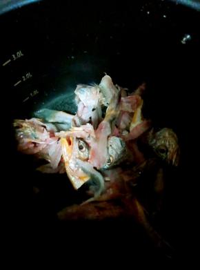 锅内加入食用油加入鱼头鱼骨煸炒