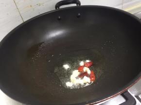 锅里倒入适量的油，把蒜和干辣椒加入