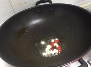 锅里倒入适量的油，把蒜和干辣椒加入