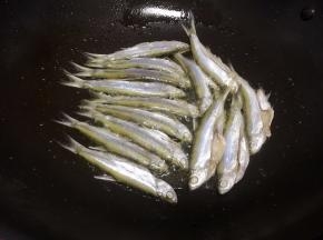 锅里放入适量的油，把腌好的小鱼加入锅里煎