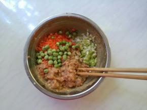 肉馅入味后，加上胡萝卜末和豌豆，最后加葱碎。