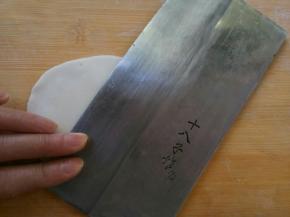 用刀背儿将面球按扁，边按薄，一圈一圈逐渐碾压成圆薄片 ，尽可能越薄越好。