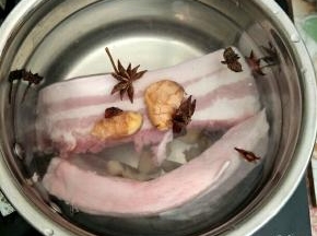 五花肉洗净冷水入锅，加入生姜、蒜头和八角煮开，水开后加入1勺料酒