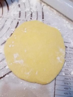 取出一小块面团，在案板上撒薄粉防粘，将面团擀开成为圆形面皮