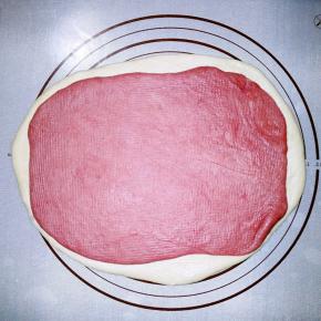 把发好的白面团排气，擀成长方形。红面团排气擀成比白面团小的长方形，并叠在白面团上。