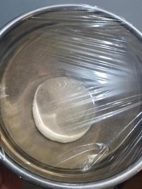 取出搅拌好的面团，揉成一块光滑的面团，装入一个小盆中，盖上保鲜膜密封，进行一次发酵