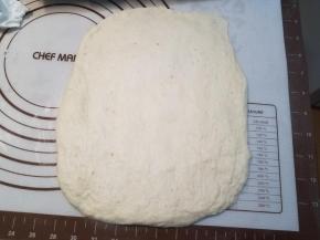 醒好面团后，用擀面杖尽量擀成长方形，个别地方的小气泡按掉，然后卷起来，接缝处捏合