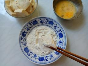 豆腐在面粉里两面蘸匀，抖掉浮粉。