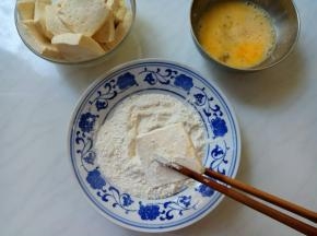 豆腐在面粉里两面蘸匀，抖掉浮粉。