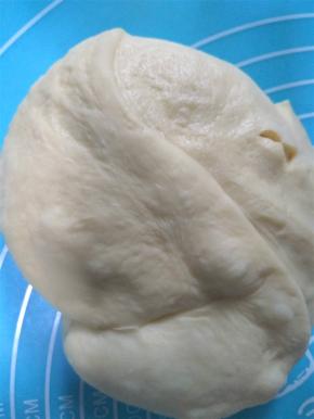操作台和面团上撒上薄粉防粘，将面团取出，轻轻按压面团，进行排气