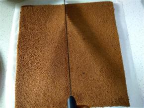 取一张油纸铺好，将凉透的蛋糕坯倒扣在上边，揭掉油布，再翻过来，横竖各切一刀，切成4块。