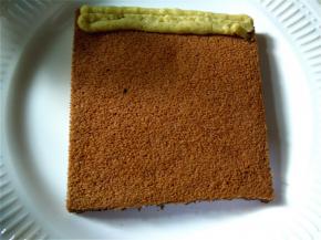 取一块蛋糕放在盘子上，将裱花袋下边剪一个大小合适的小口，在蛋糕上均匀挤上栗子奶油馅。