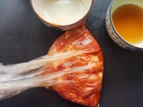 把鸡腿肉切2块装入保鲜袋，把料酒和奥尔良腌料一起倒入，均匀涂抹，腌制半小时
